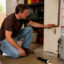 Homeowner turning off the main water shut-off valve in a garage